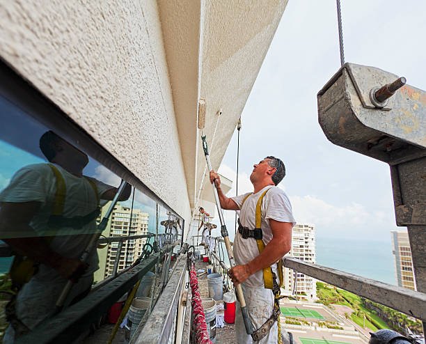 Two painters are painting a high rise building from a swing stage.